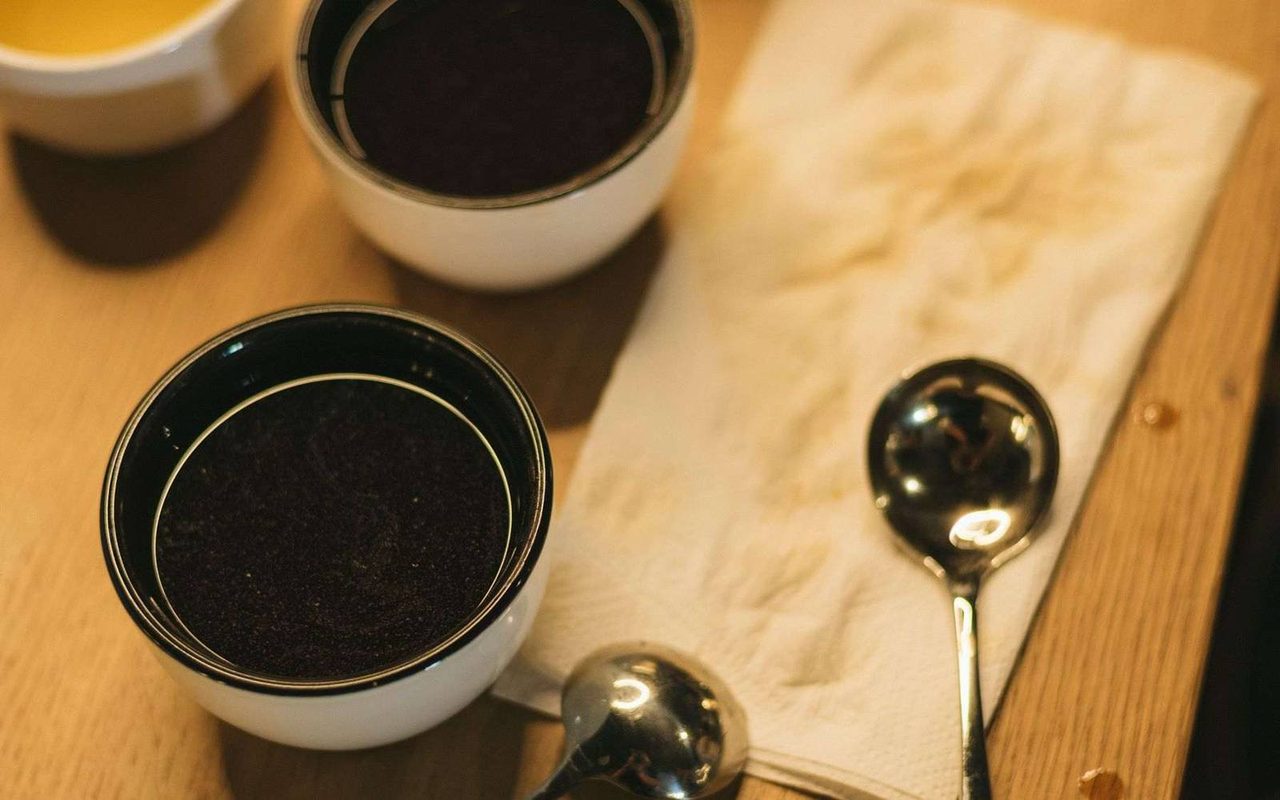 Cupping-Tisch in Aufsicht mit einer Reihe Schalen, Löffeln und Wassergläsern