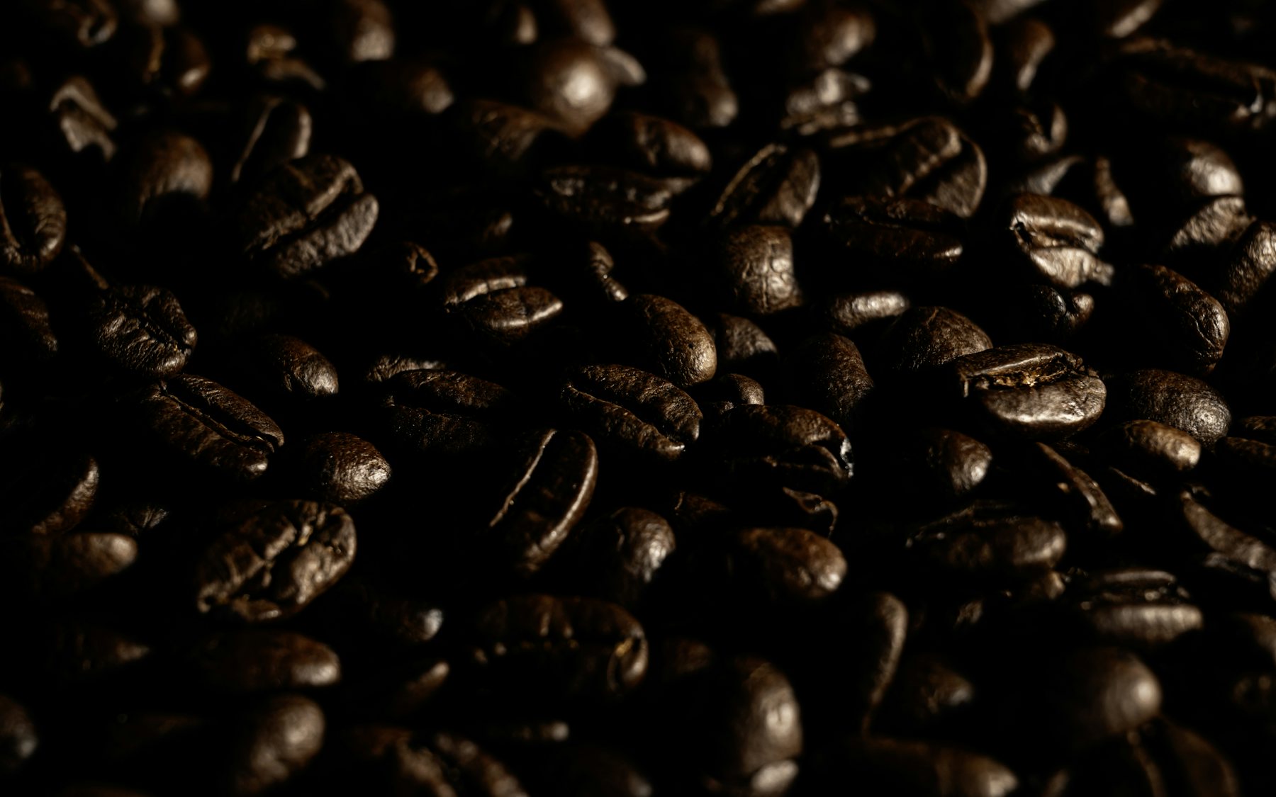 Geröstete Kaffeebohnen in warmem Braun, formatfüllend von oben aufgenommen