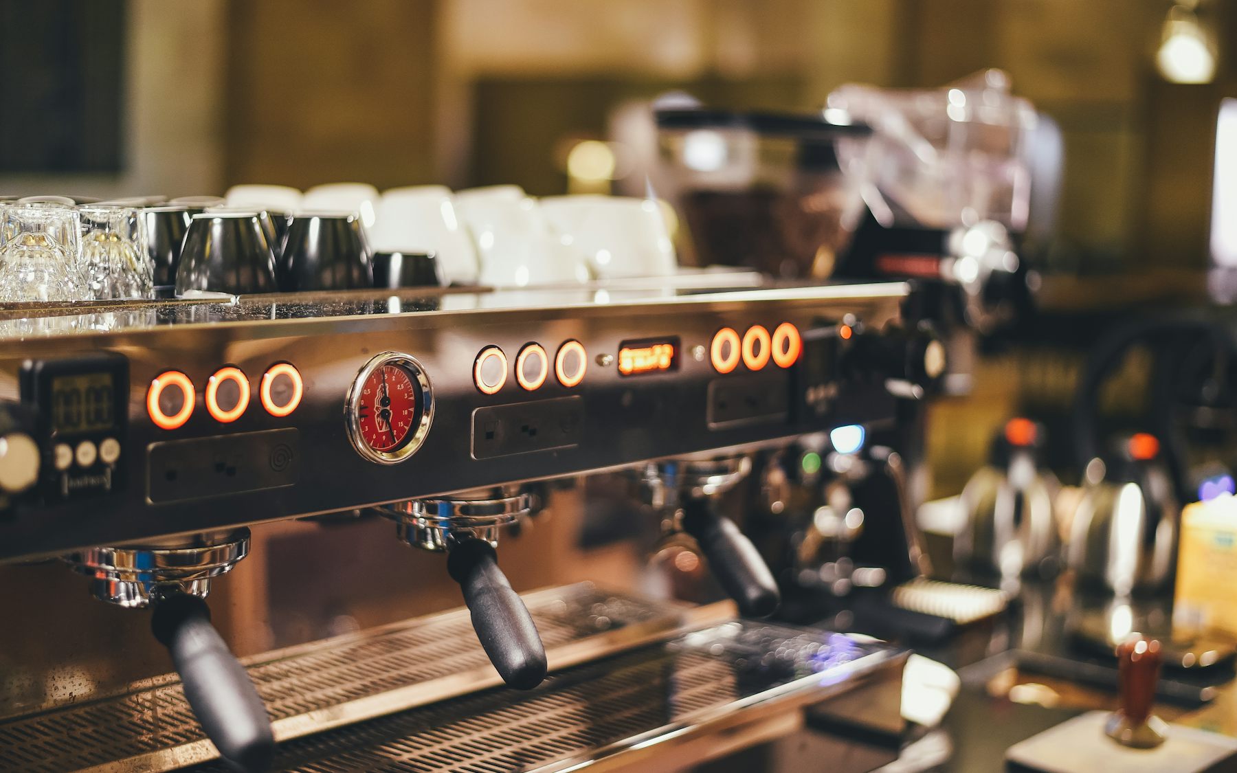 Cafetheke mit Siebträgermaschine in einem Backsteinspeicher bei Tageslicht, Gebäck im Vordergrund